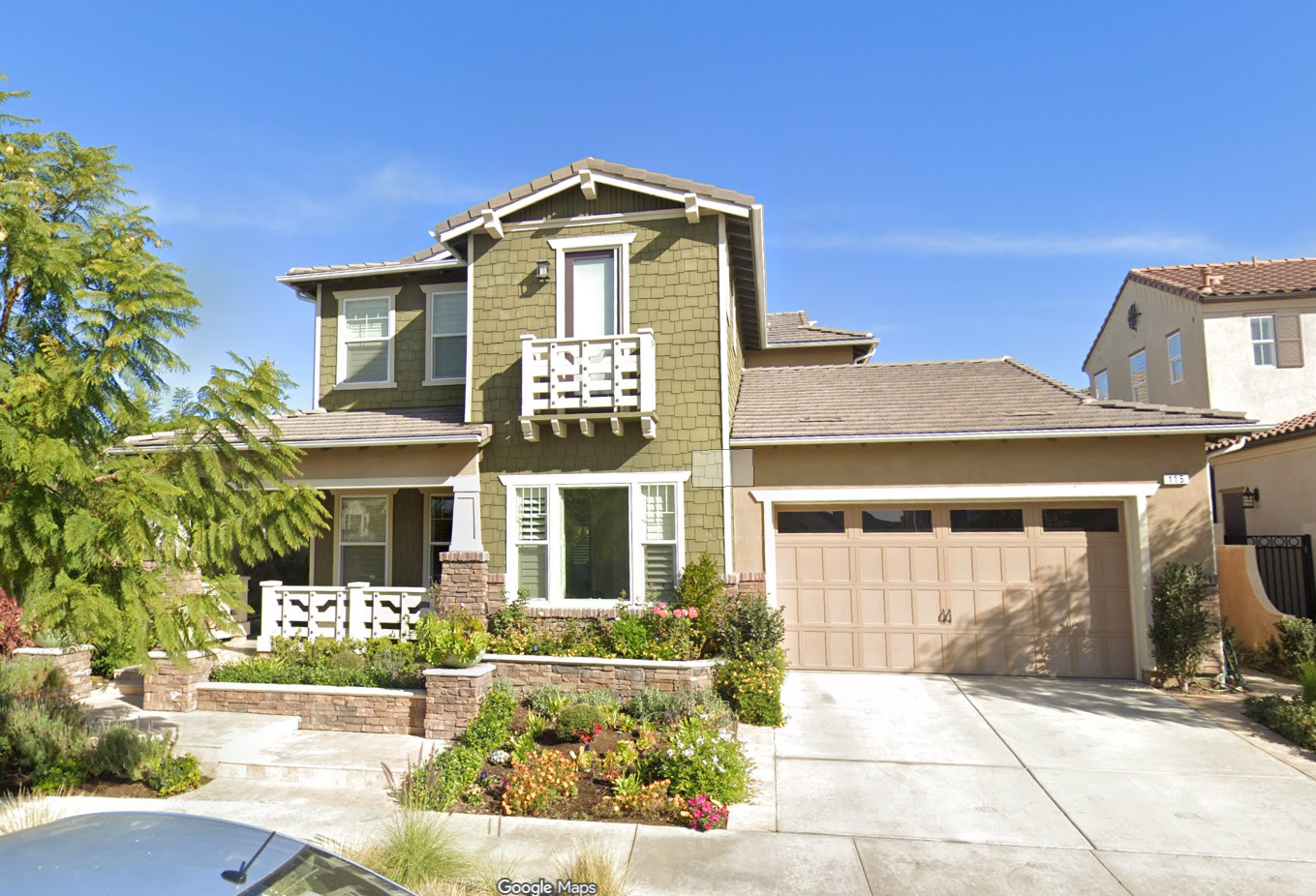 California real estate house with green exterior, balcony, garage, and plants.
